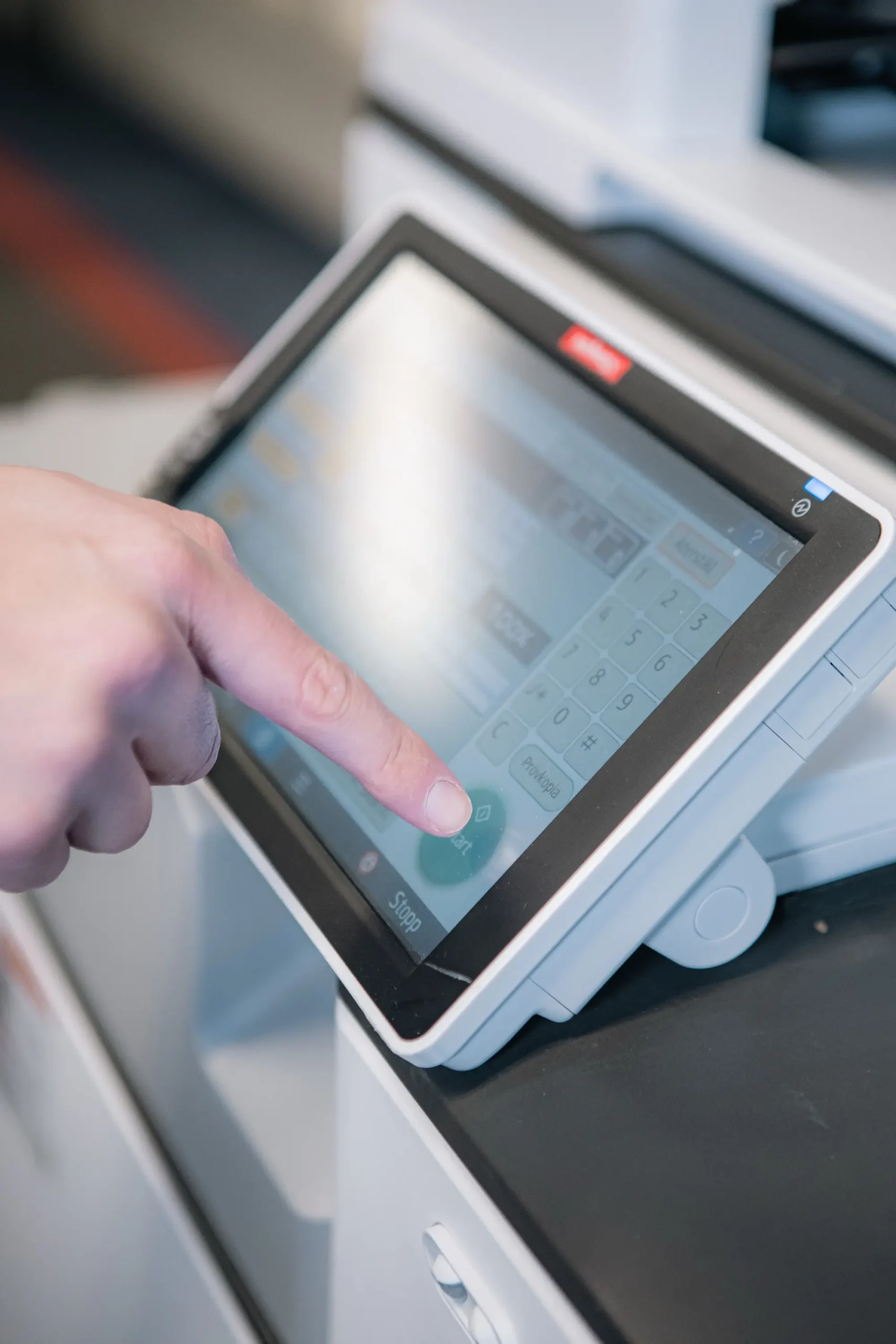 En hand som trycker på en skrivares touch-display