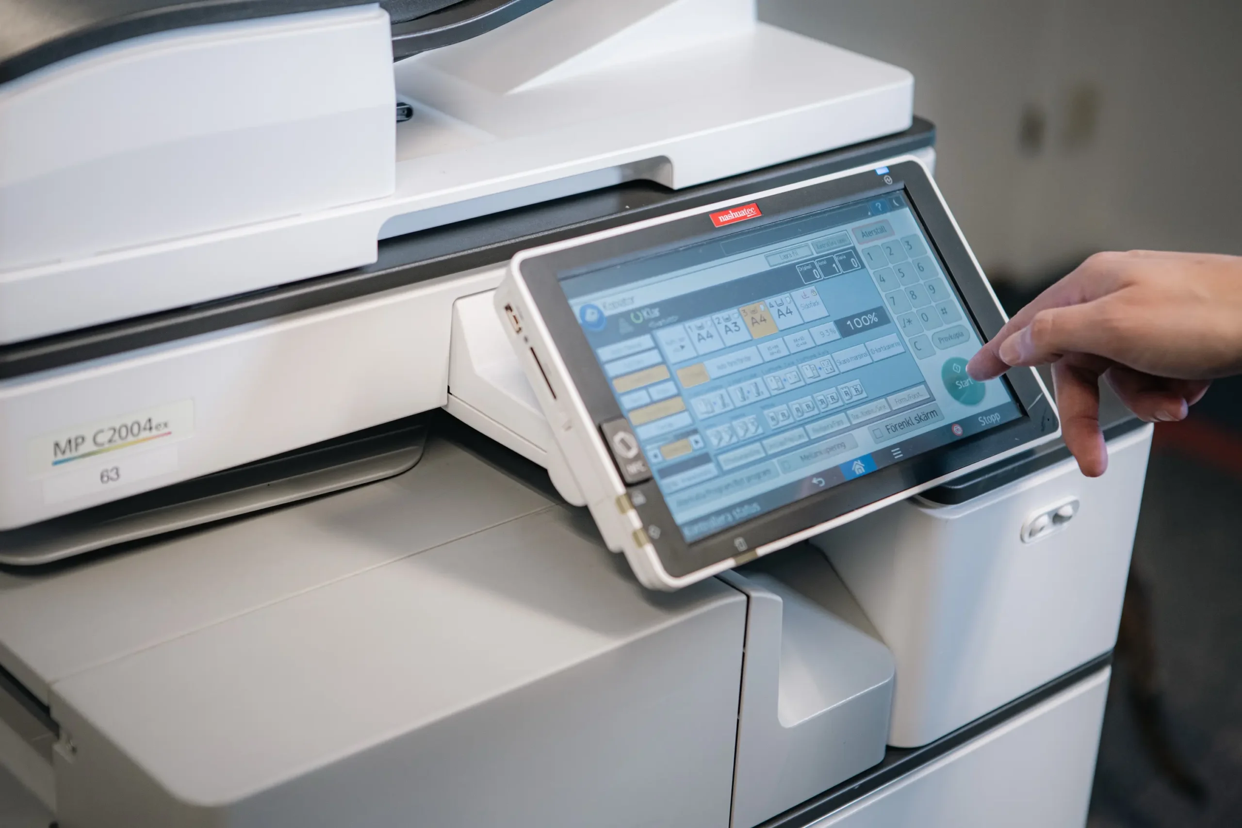 En hand som trycker på en skrivares touch-display